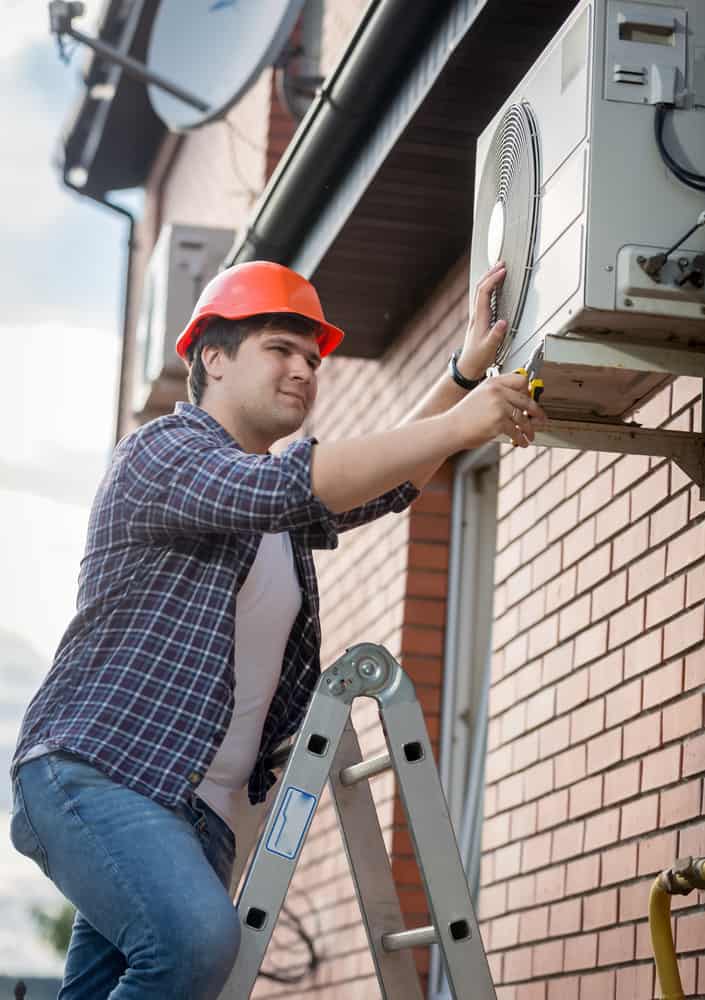 hvac technician installing outdoor wall mounted unit